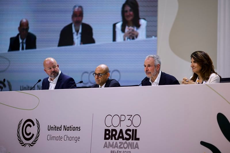 Delegates at COP30 in Belém, Brazil, discussing climate change initiatives amidst the Amazon rainforest backdrop.